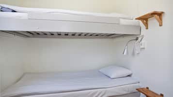 Una cama litera con un estante de madera fijado a la pared superior.