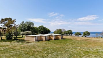 A row of mobile homes with a grassy field and trees in the background.