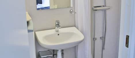 A bathroom with a sink, mirror, shower, and patterned floor tiles.