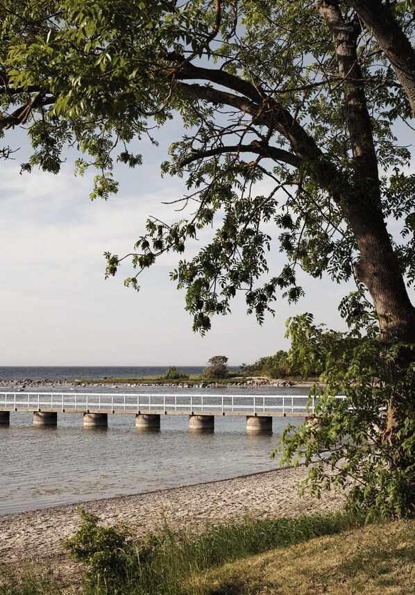 Un río con un puente de hormigón, rodeado de vegetación y un cielo despejado.