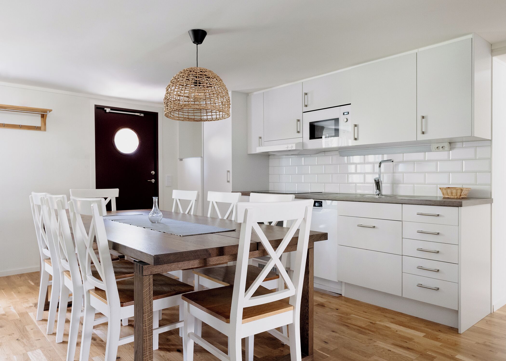Eine moderne Küche mit weißen Schränken, einem Holztisch und weißen Stühlen.