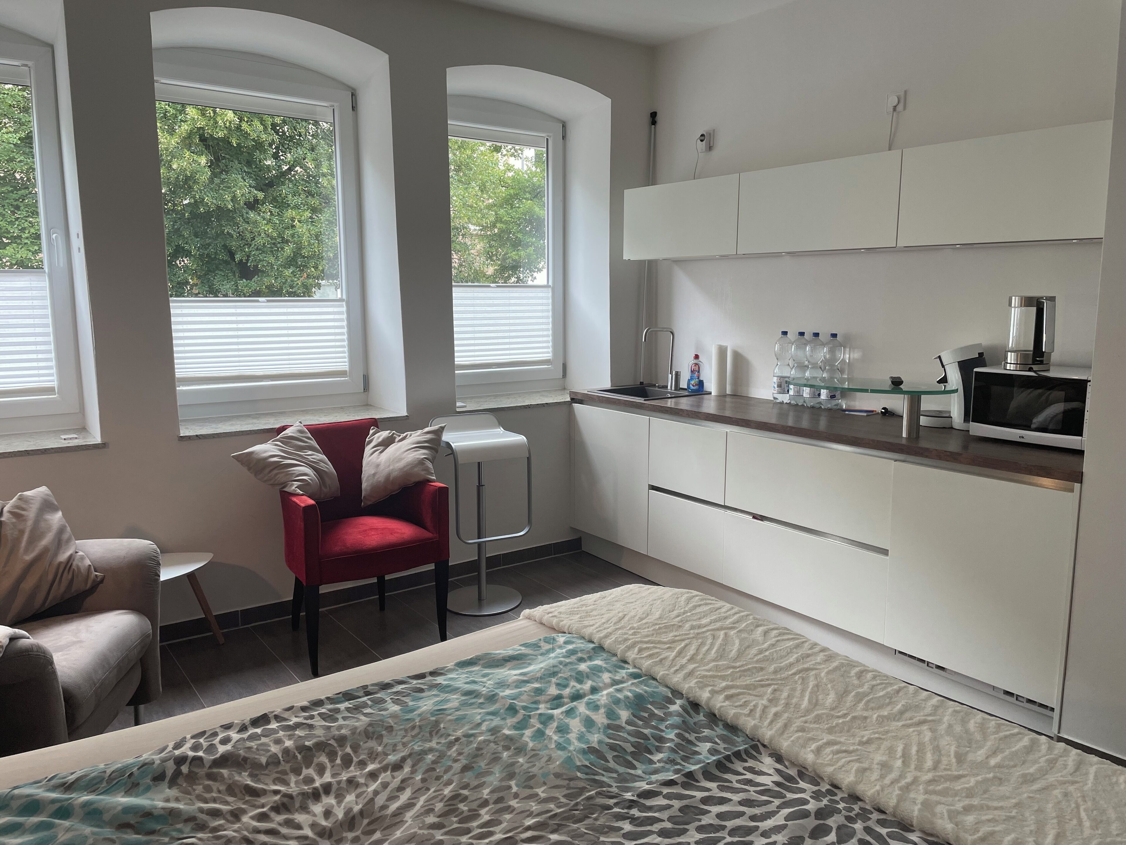 Une cuisine moderne avec des meubles blancs, une chaise rouge et une table en verre.