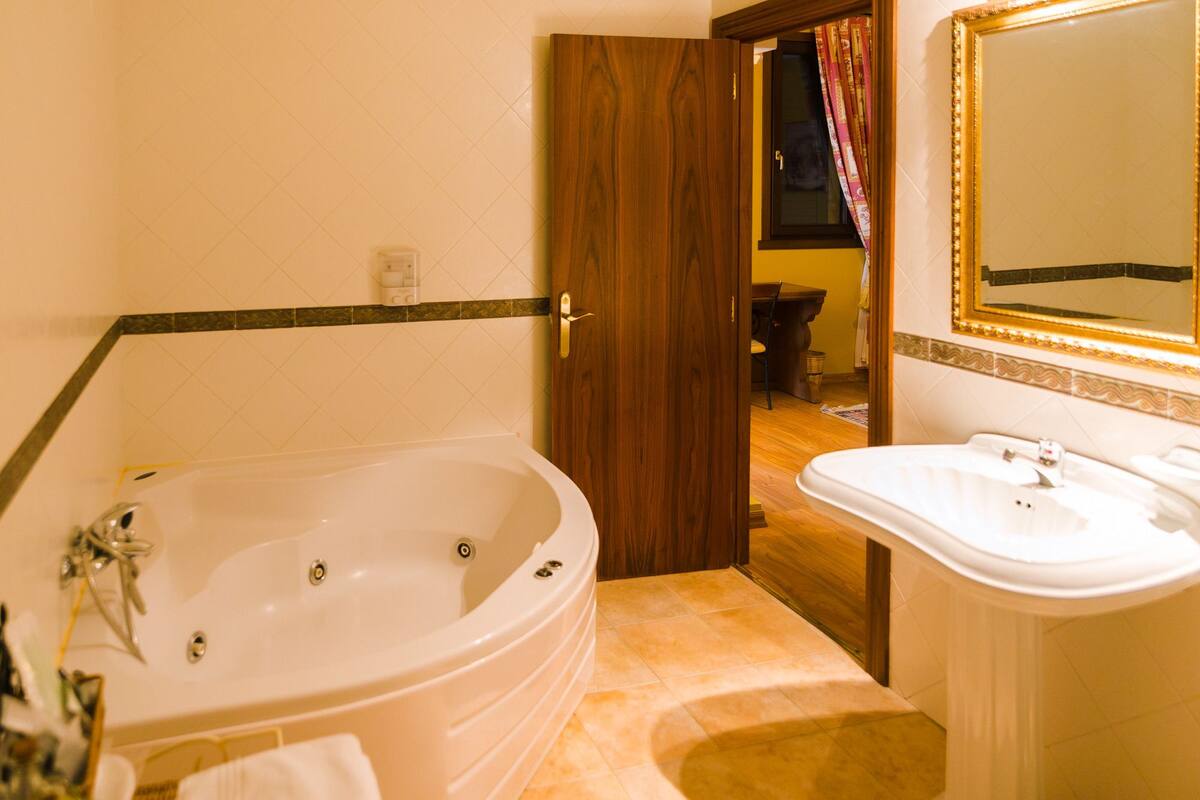 Ein Badezimmer mit einer großen Badewanne, einem Waschbecken und einem Spiegel.