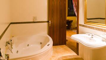 Une salle de bain avec une grande baignoire, un lavabo et un miroir.