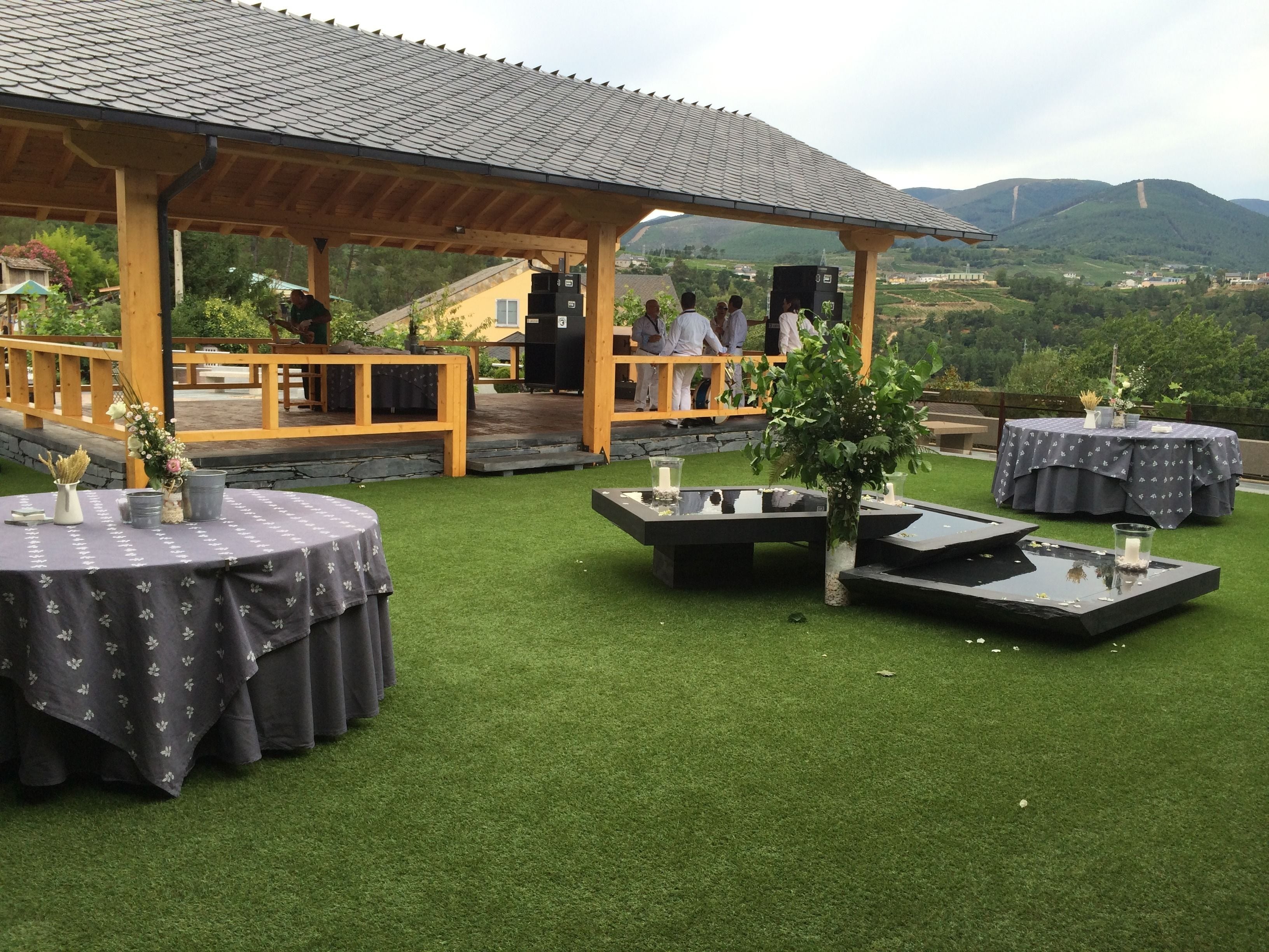 An outdoor patio with tables and planters, a covered seating area, and a view of the surrounding landscape.
