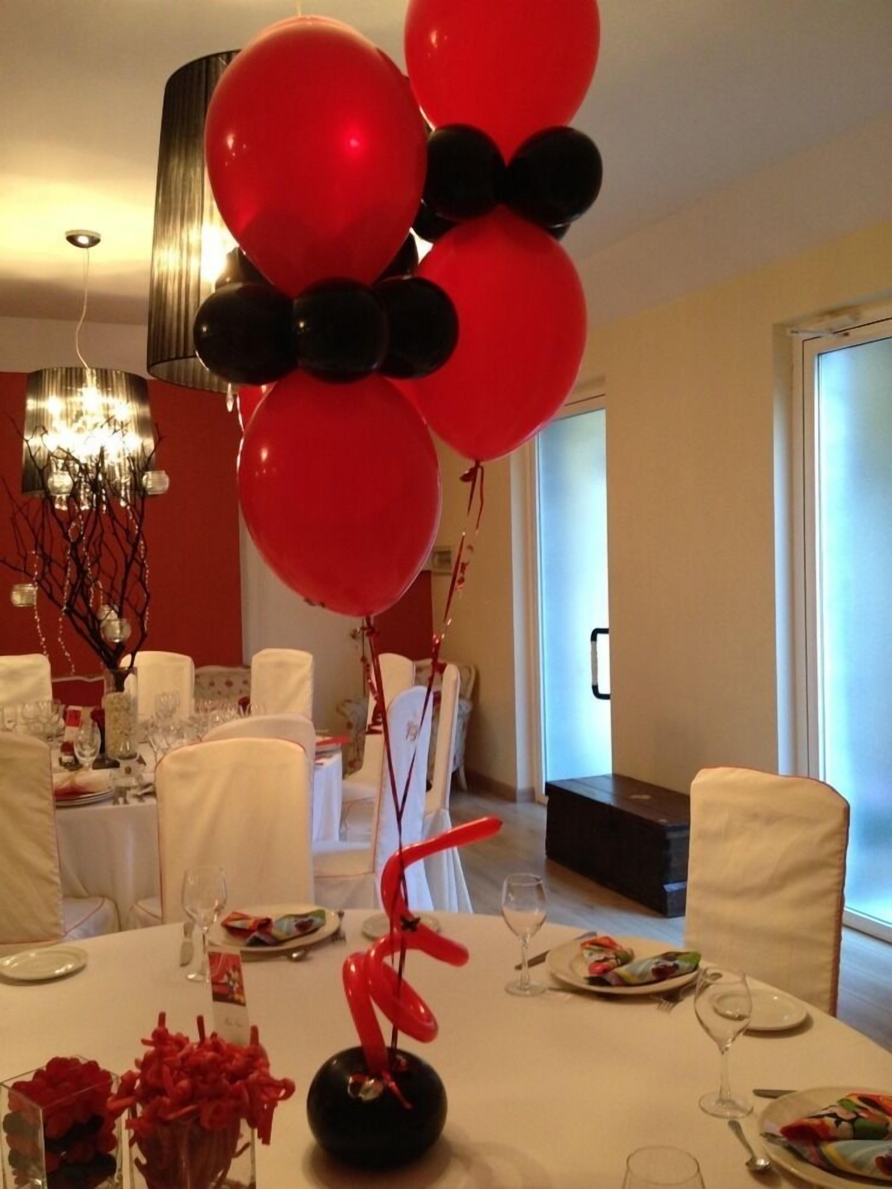 Un comedor con una mesa dispuesta para comer, globos y una escultura decorativa.