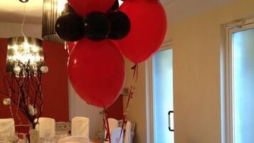 Un comedor con una mesa dispuesta para comer, globos y una escultura decorativa.
