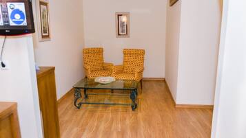 A narrow hallway with a checkered armchair and a glass table.