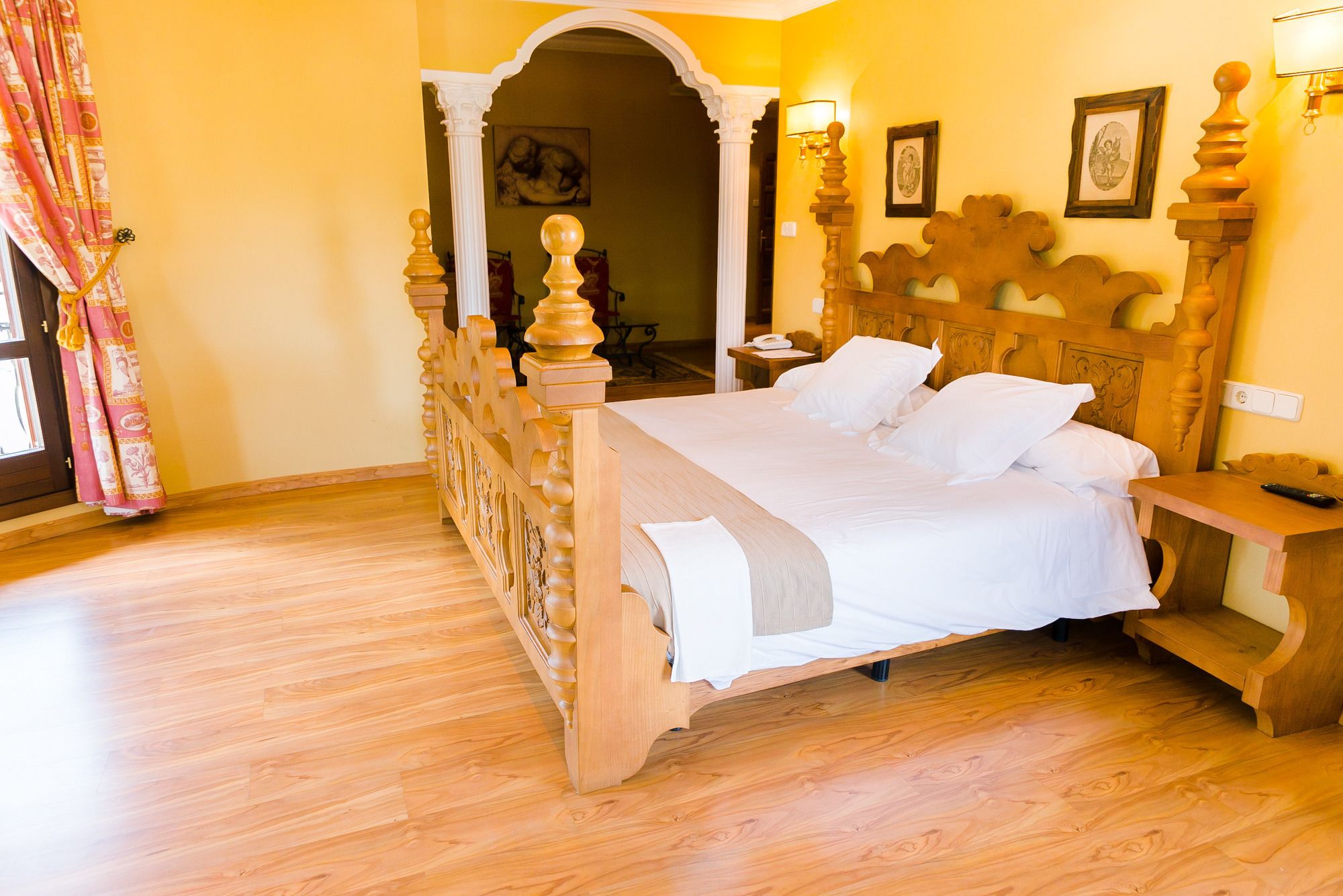 A bedroom with a wooden bed, a nightstand, and a wall-mounted lamp.