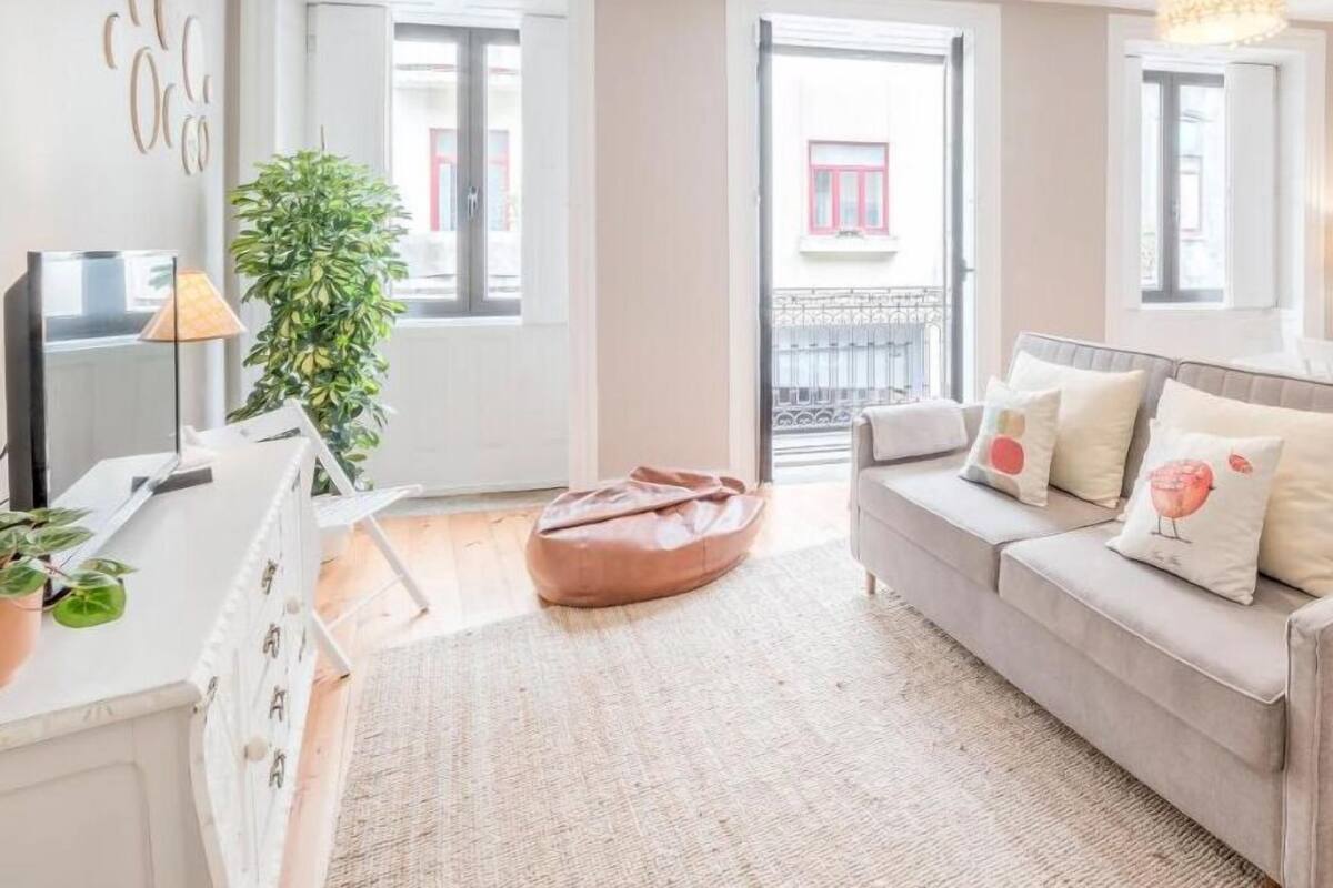 A modern living room with a sofa, a coffee table, a lamp, and a potted plant.