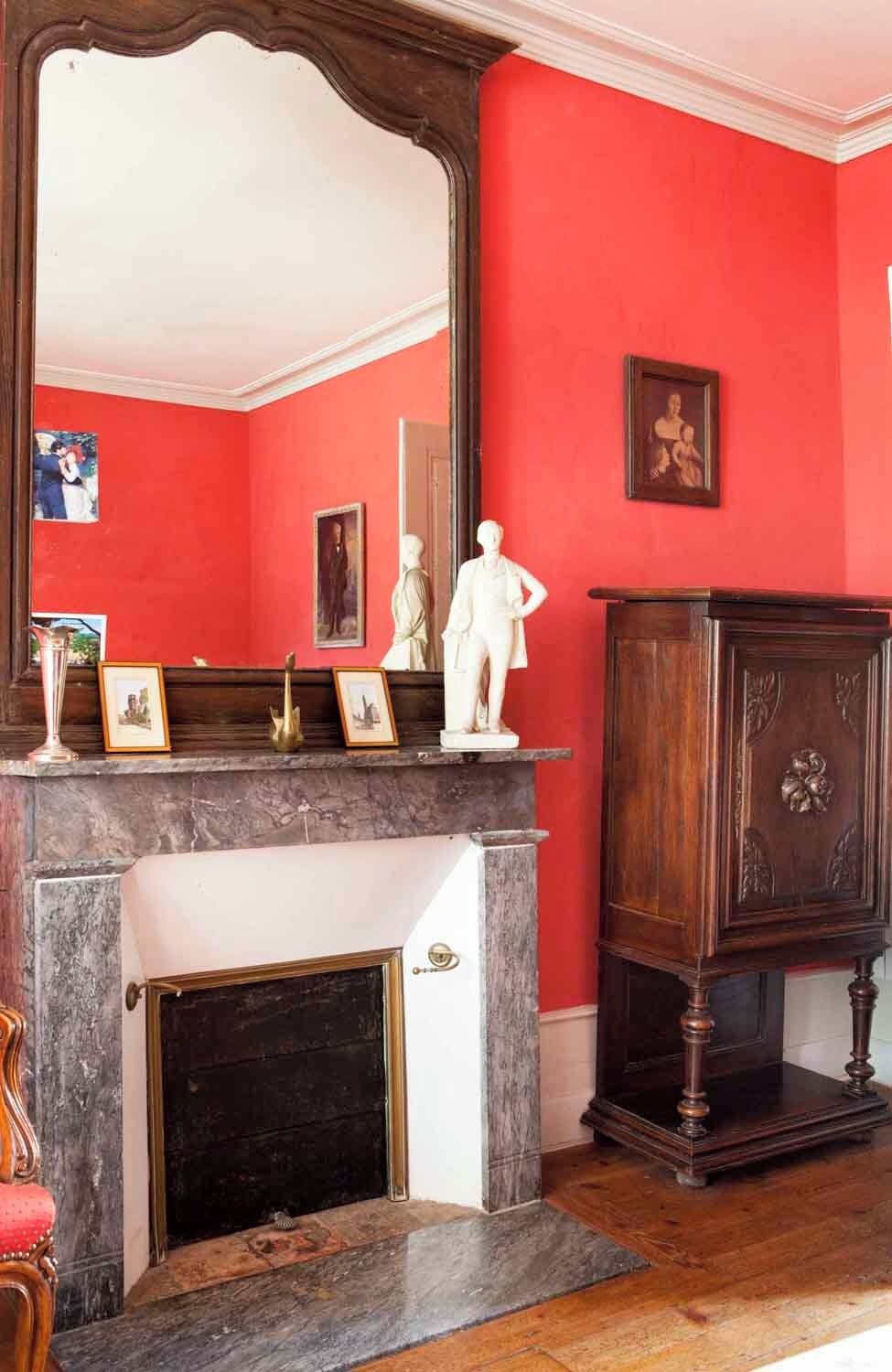 A room with a fireplace, a large mirror, and a statue on the mantel.