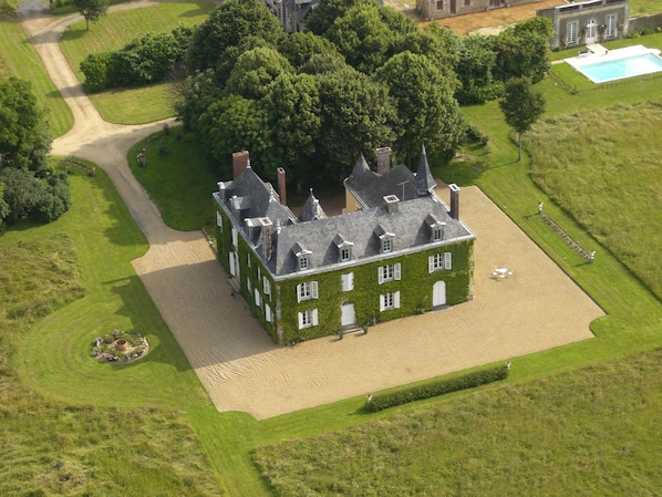 An aerial view of a large, historic building with a symmetrical facade, surrounded by well-maintained lawns and a clear sky. - Château des Lutz (Daon)