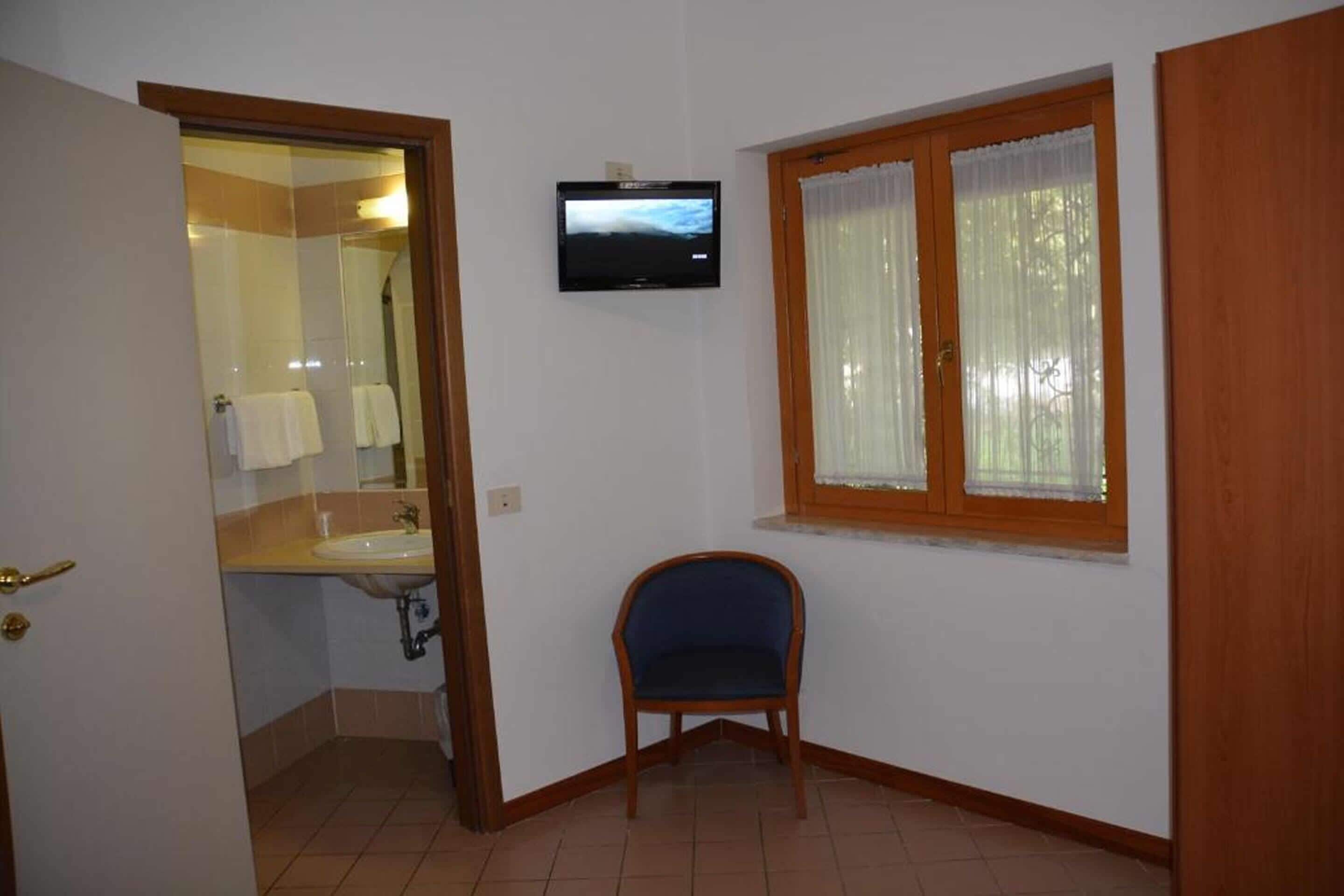 A bathroom with a sink, mirror, and a television mounted on the wall.