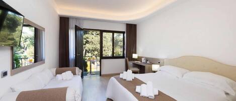 Ein Hotelzimmer mit zwei Betten, einem Schreibtisch, einem Sessel und einem Fernseher.