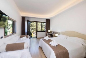 Une chambre d’hôtel avec deux lits, un bureau, une chaise et une télévision.