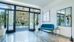 A modern interior with a blue sofa, a large mirror, and a potted plant.