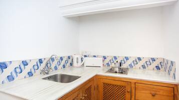 Una cocina con encimeras blancas, un lavamanos, un hervidor y un tostador.