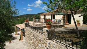 A stone-walled building with a tiled roof, a metal fence, and potted plants. - Agroturismo Son Not (Arta)