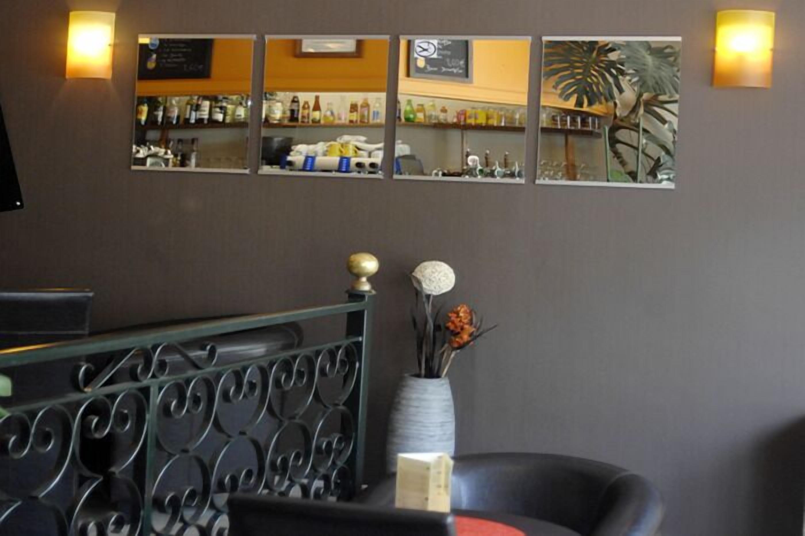 Angolo bar con un bancone, scaffali pieni di bottiglie e uno specchio decorativo con una pianta.