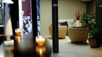 Een moderne lobby met een zithoek, een receptiebalie en een decoratieve plantenstelling.