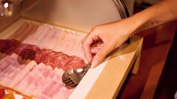 A hand selecting ham from a display case.