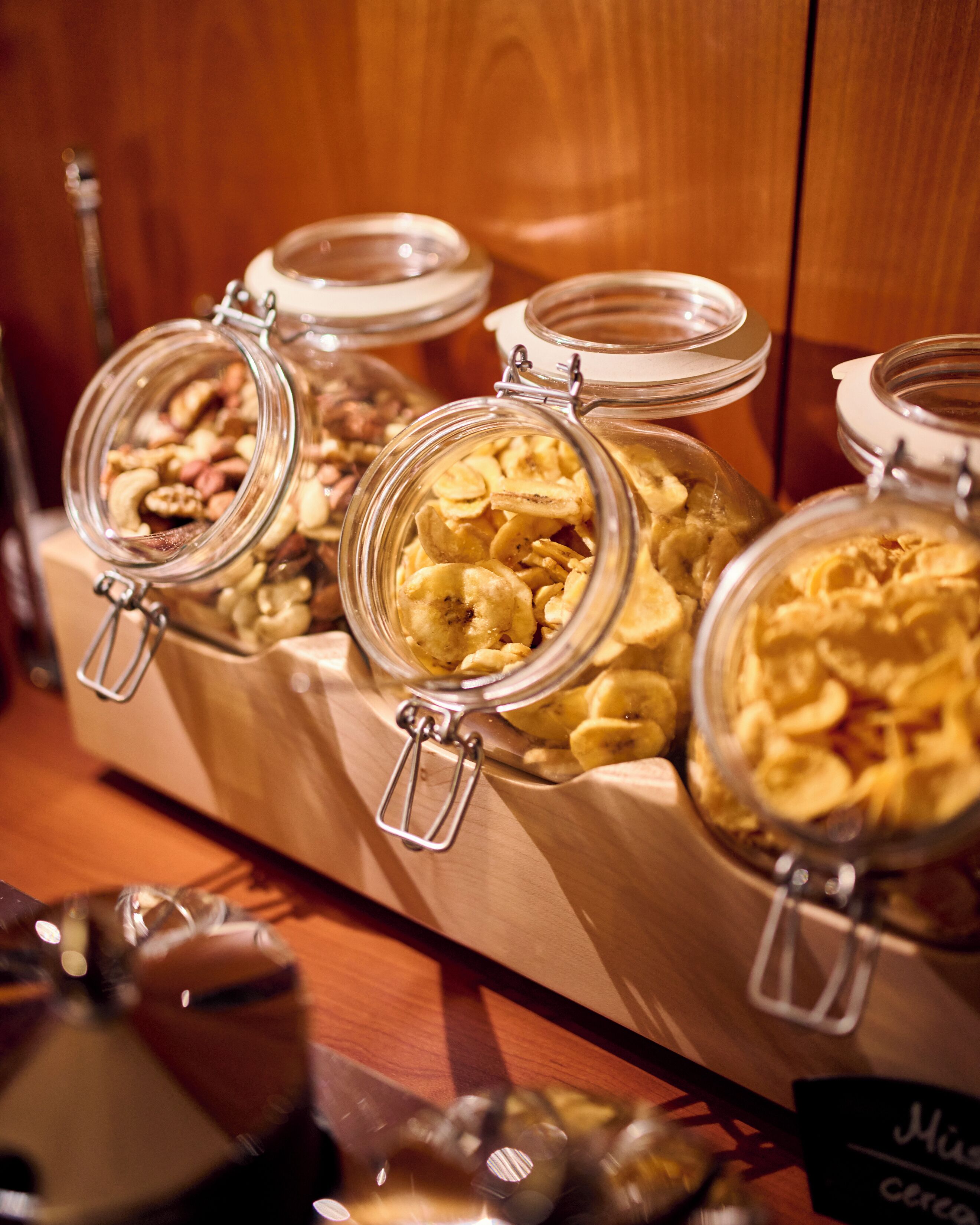 Una exhibición de diversos alimentos en frascos de vidrio con cierres metálicos, dispuestos sobre una superficie de madera.