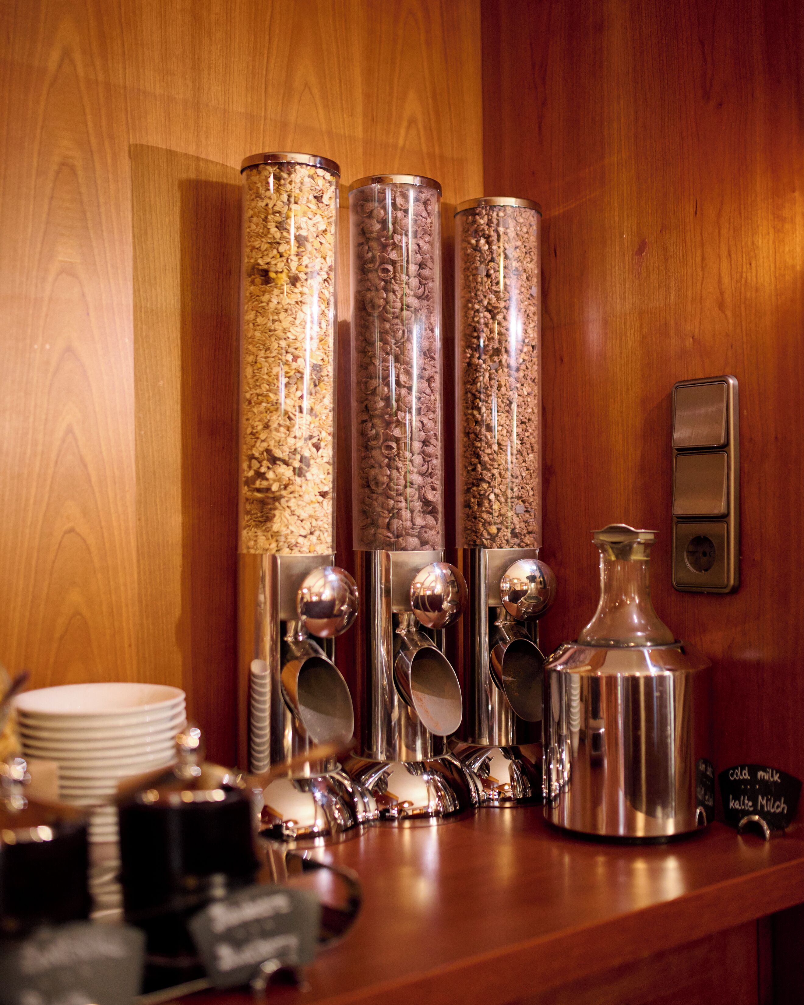 A bar area with multiple coffee dispensers, a milk frother, and a coffee pot.