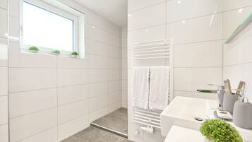 Un baño moderno con ducha, lavamanos y ventana con plantas.