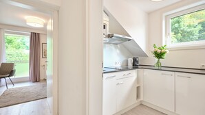 Una cocina moderna con armarios blancos, encimera negra y ventana con vistas al verdor.