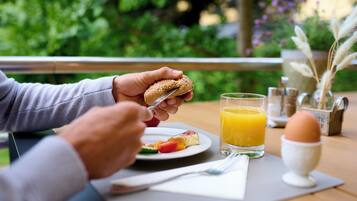 En frukostuppläggning med en smörgås, juice och ett ägg på ett bord.