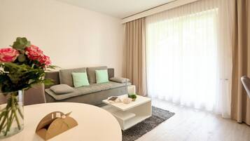 Una sala de estar moderna con un sofá gris, una mesa de centro blanca y un jarrón con flores.