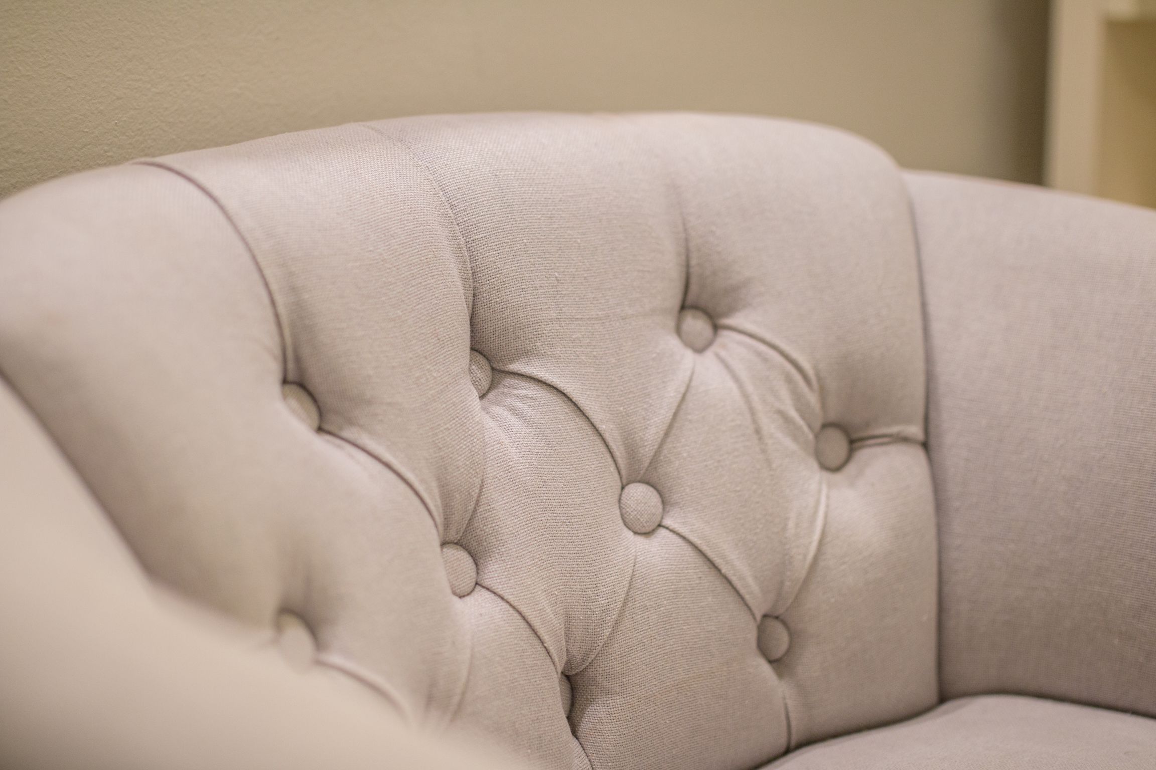 A close-up of a tufted, upholstered chair with a buttoned design.