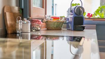 A kitchen counter with a coffee maker, a basket, and a jar labeled "CUPRESSIONE".