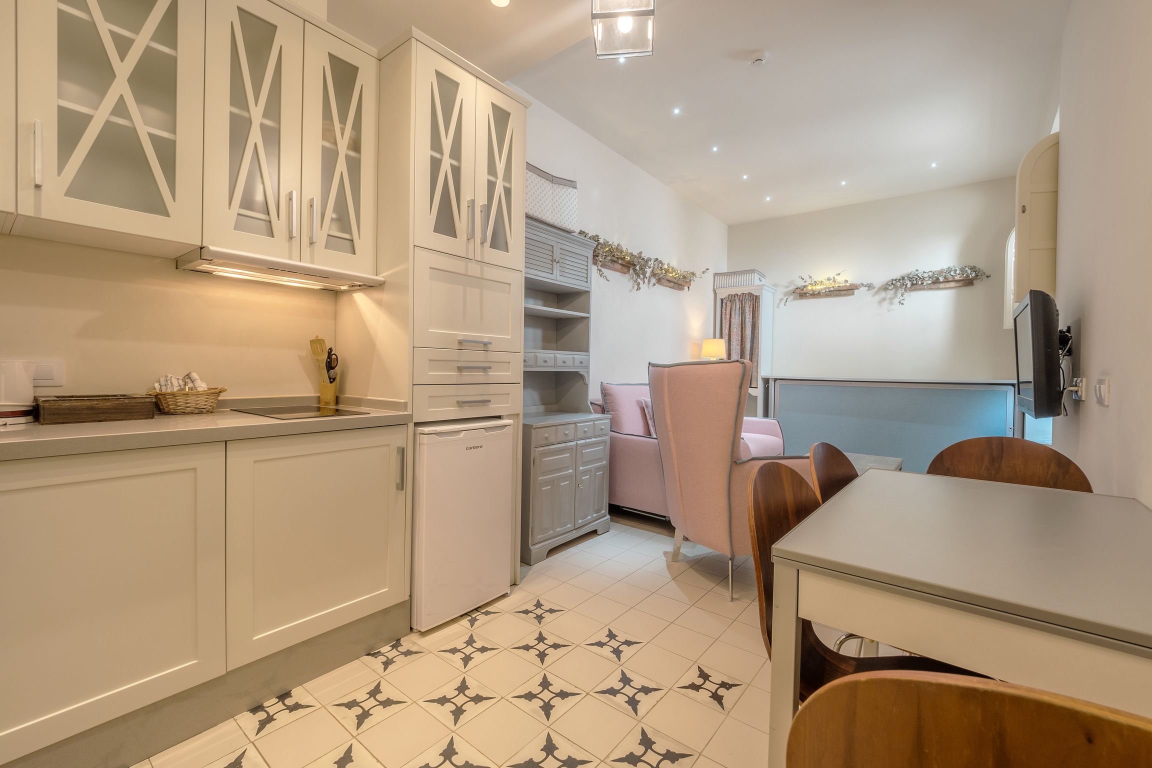 A compact kitchen with white cabinetry, a refrigerator, and a dining area with a table and chairs.