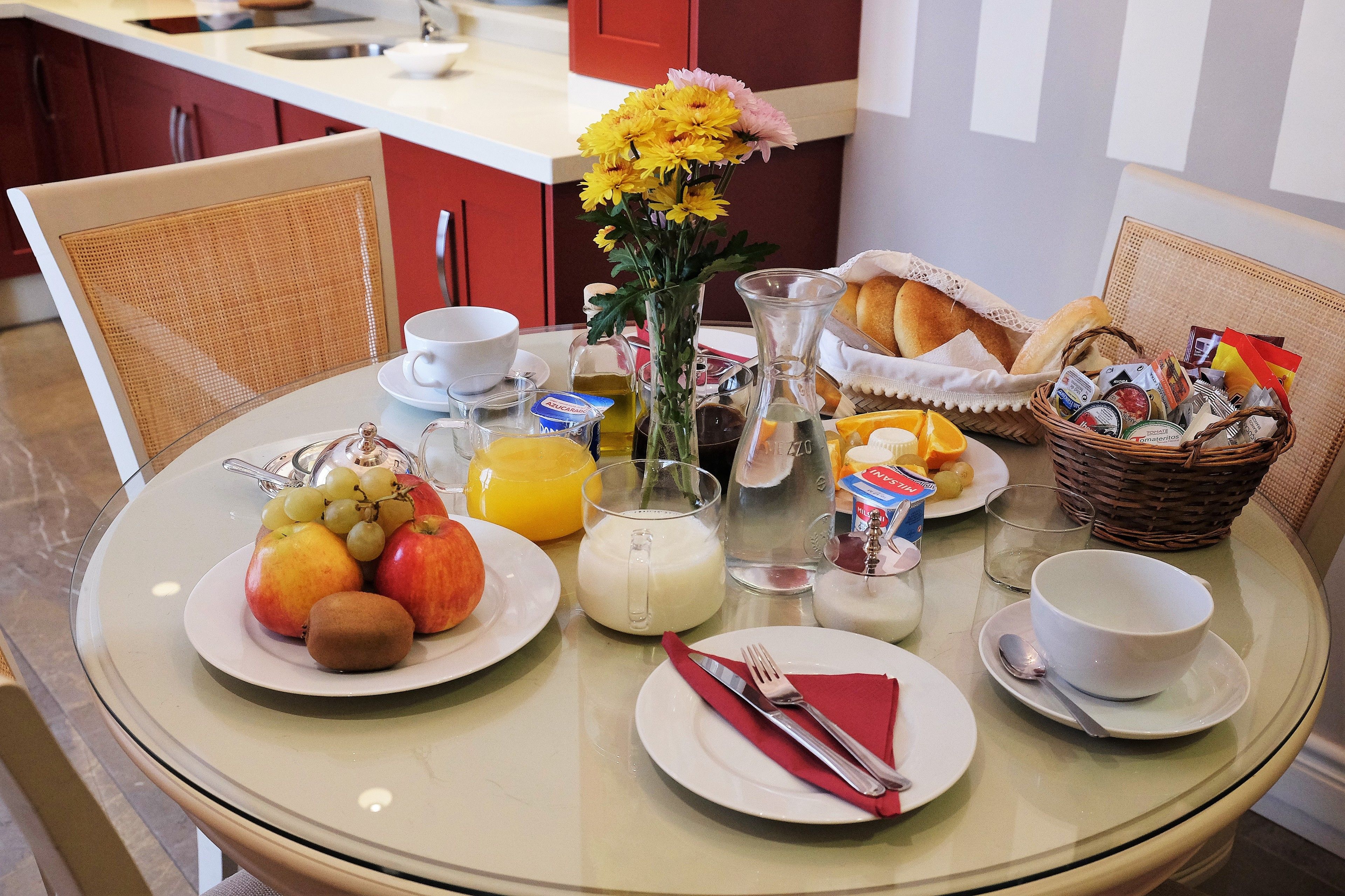 Ein Esstisch mit Fruchtschalen, einer Blumenvase und verschiedenen Frühstücksangeboten.