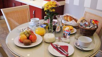 Ein Esstisch mit Fruchtschalen, einer Blumenvase und verschiedenen Frühstücksangeboten.