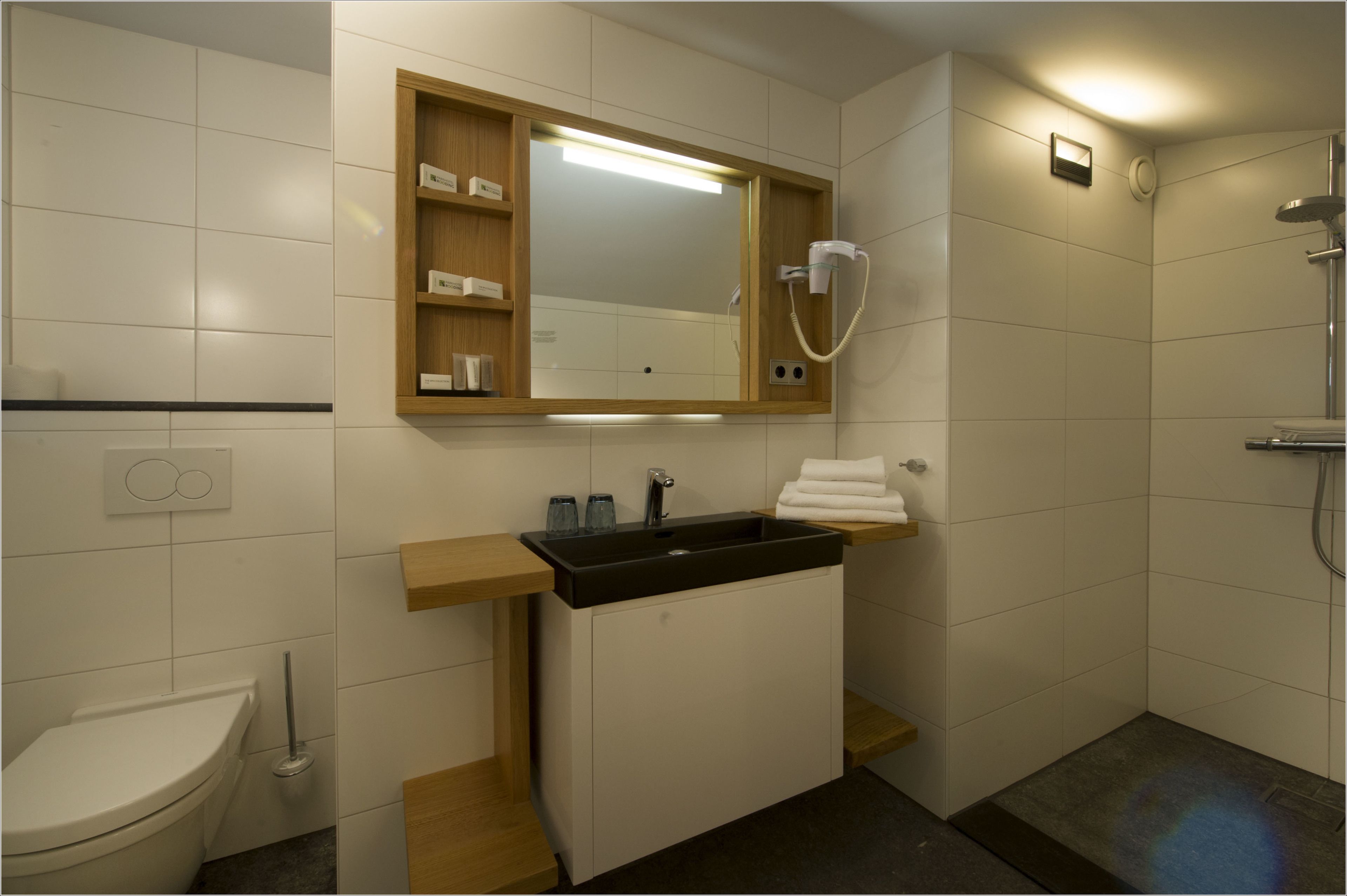A modern bathroom with a sink, mirror, and shower.