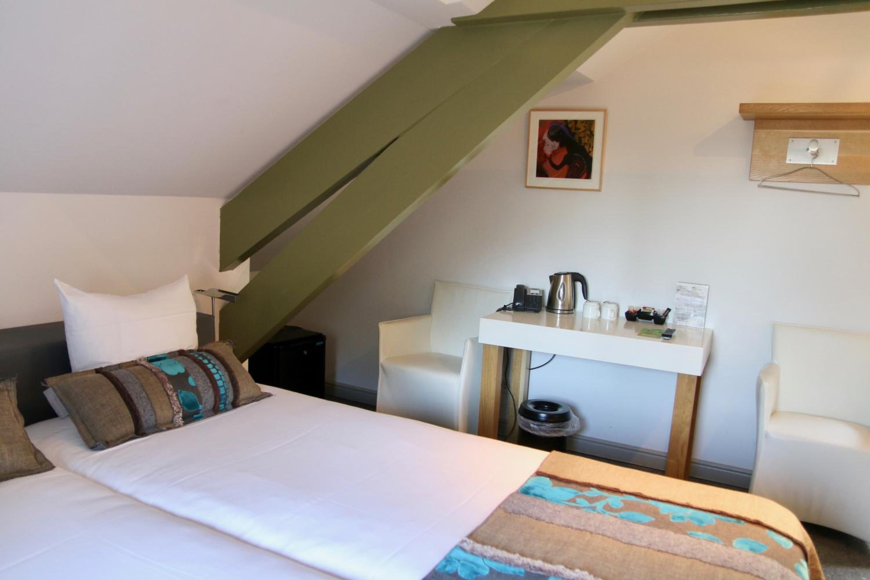 Un dormitorio con cama, escritorio y silla.