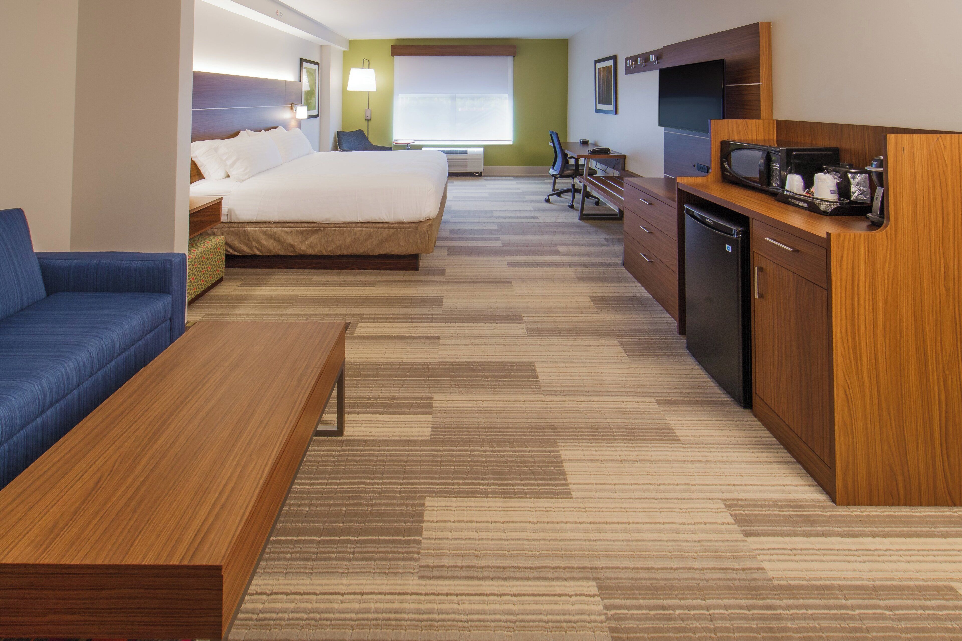 Una habitación de hotel con cama, sofá, escritorio con microondas y refrigerador.