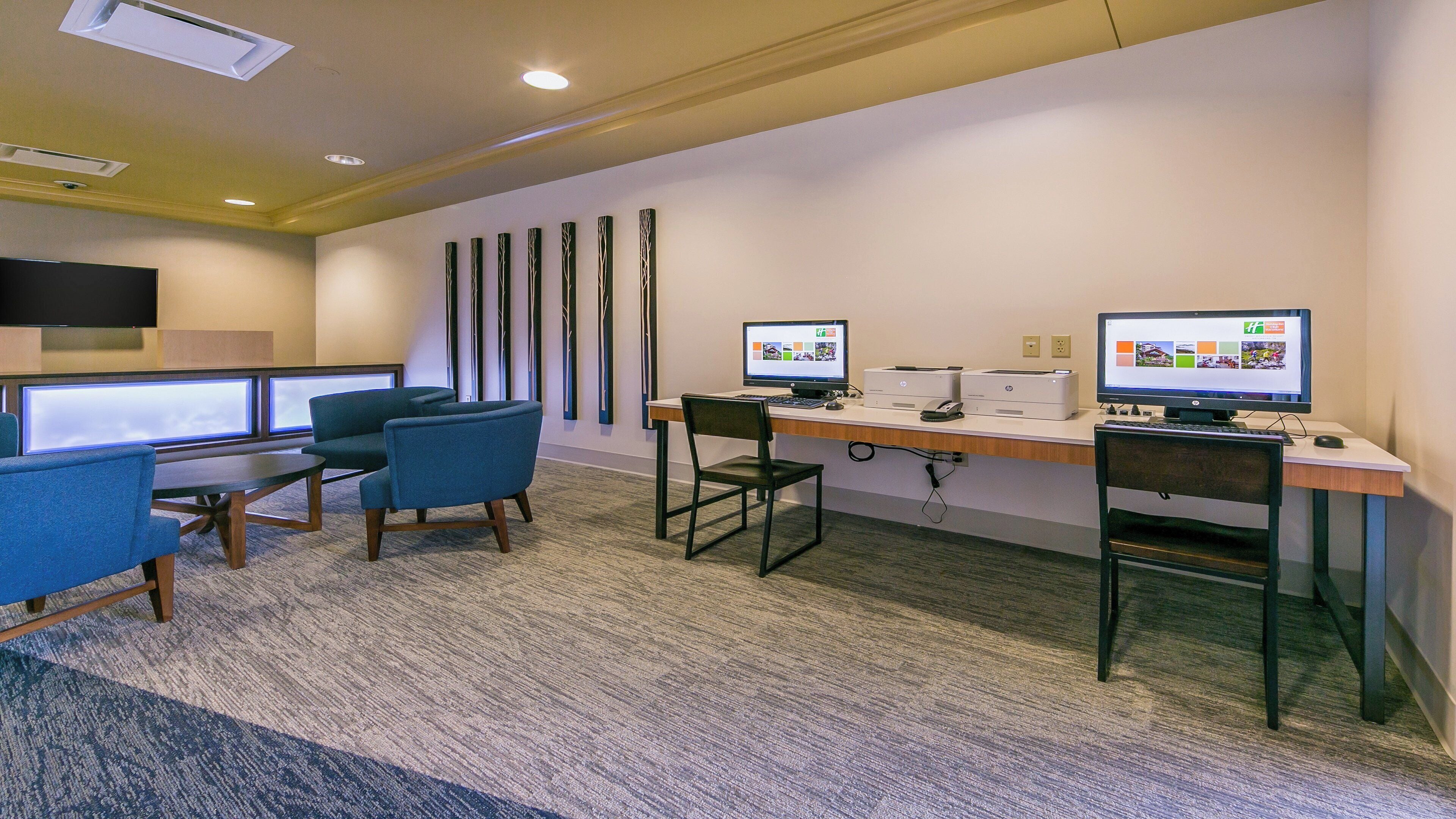 A modern office space with two desks, chairs, computers, and a flat-screen TV.