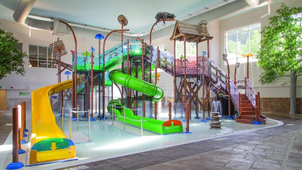 Ein Indoor-Spielbereich mit Rutschen und Klettergerüsten.