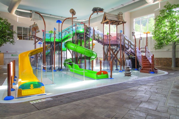 Un espace de jeux intérieur avec des toboggans et des structures d’escalade.