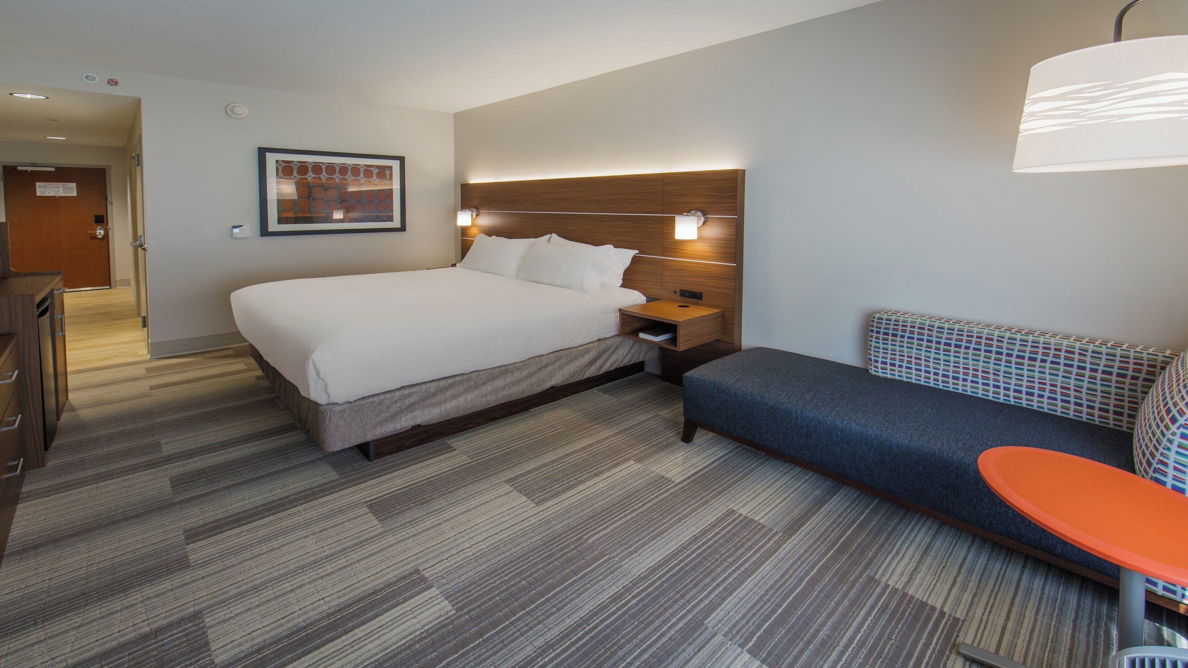 Quarto de hotel com cama, mesa de cabeceira e área de estar com uma mesa.