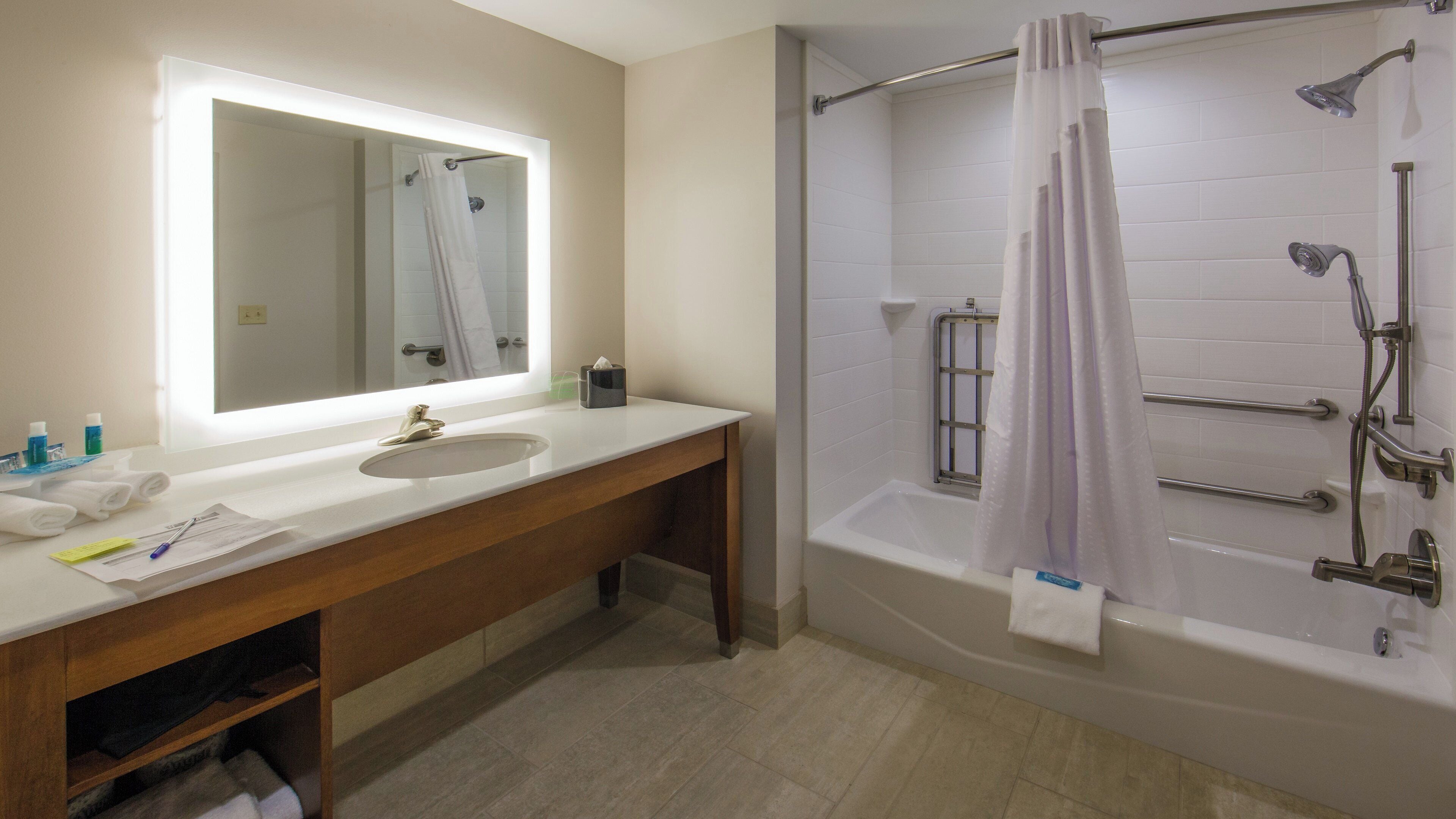 Een badkamer met een wastafel, spiegel en douche.