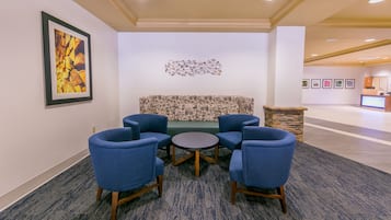 A lobby with a seating area featuring a sofa and four chairs, a reception desk, and framed artwork on the walls.