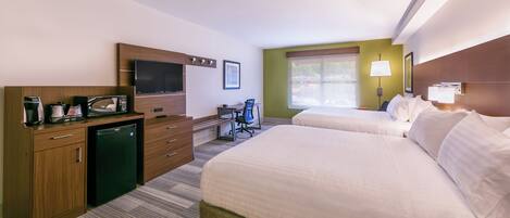 A hotel room with two beds, a desk with a chair, a television, a coffee maker, and a window with a view.