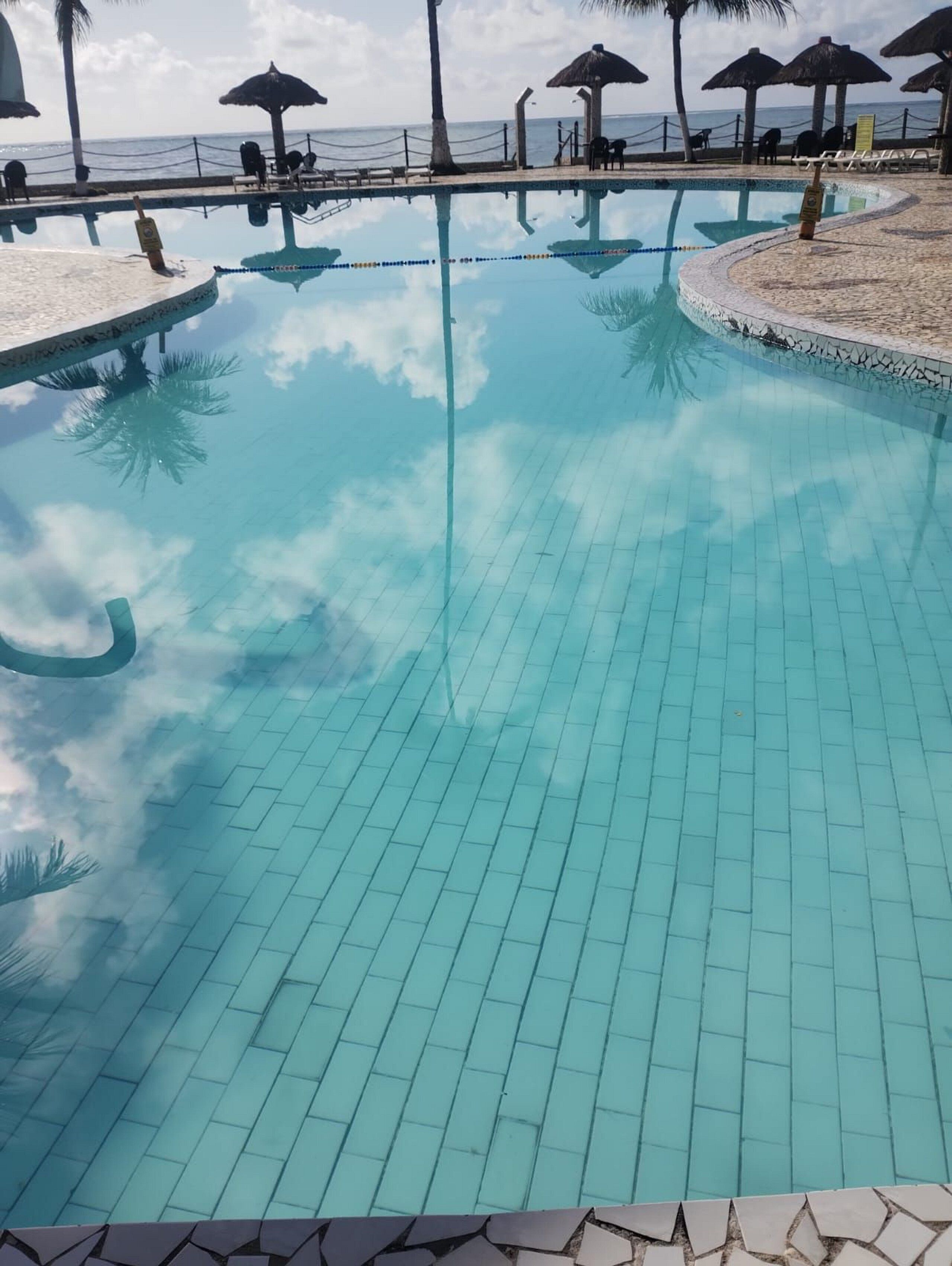 Una piscina al aire libre, sombrillas, sillones reclinables de piscina