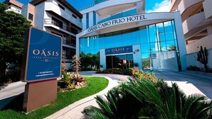 The OASIS CABO FRIO HOTEL with a modern facade, large glass windows, and a well-maintained garden area. - Oásis Cabo Frio Hotel (Cabo Frio)