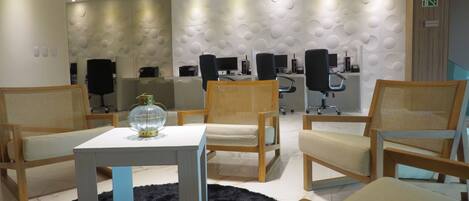 A modern waiting area with wooden chairs, a white table, and a black furry rug.