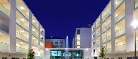 A modern hotel with a central courtyard, glass railings, and a fountain.